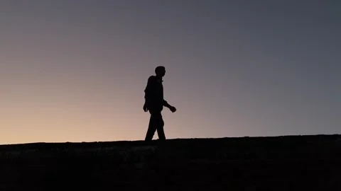 Silhouette Man Walking on Bridge Captured from Below During Sunset Stockbeeldmateriaal 320828018