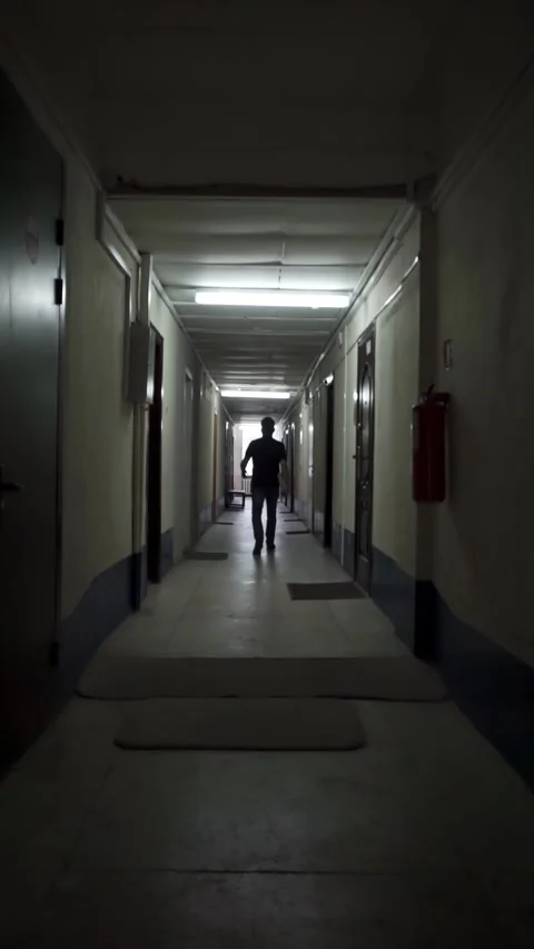 A silhouette of a man walking down a dark corridor of an office building Stock Footage 286100985