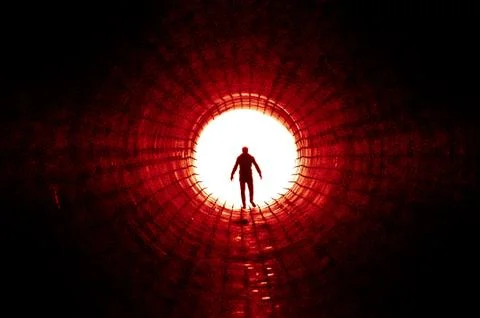 Silhouette of a man walking to the light at the end of a big tunnel. Concept of Stock Photos
