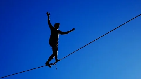 Silhouette of a man walking on a tightrope against the sky. Rope-walker. Stock Footage