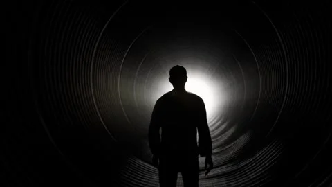 Silhouette of Man Walking Towards Light in Dark Tunnel Stock Footage 315920672