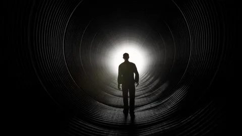 Silhouette of Man Walking Towards Light in Dark Tunnel Stock Footage 315920736