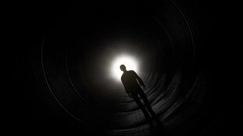 Silhouette of Man Walking Towards Light in Dark Tunnel Stock Footage 315920790