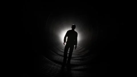 Silhouette of Man Walking Towards Light in Dark Tunnel Stock Footage 315920831