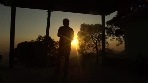 Silhouette of Man Walking Towards the Setting Sun at Sunset Stock Footage 345630707