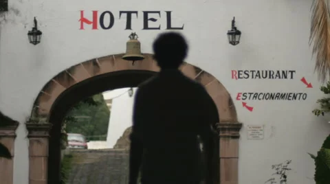 Silhouette of a man walking under an arch at a Mexico hotel Stock Footage 66690944