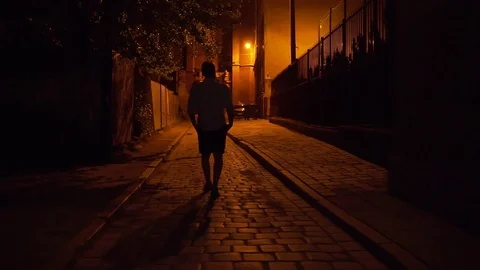 Silhouette. A man walks through the night city narrow street in the night one Stock Footage 127299976