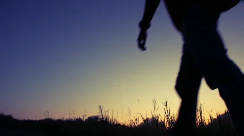 Silhouette of man walks uphill against sky Stock Footage