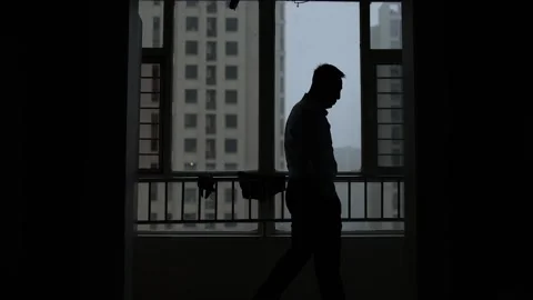 Silhouette of a man wandering in front of the window thinking Stock Footage 164634480