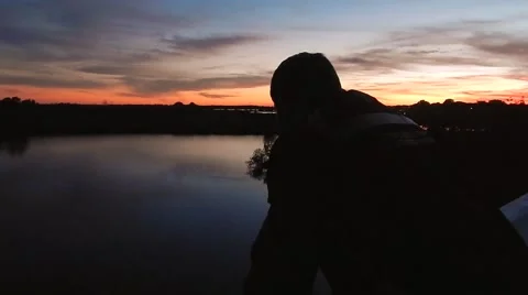Silhouette of man watching sunset over water Vídeos de archivo 45297239