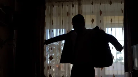 Silhouette of a man wearing a jacket in front of the window Stock Footage 101571509