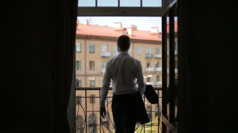 Silhouette of a man wears a jacket standing on the balcony of the hotel Stock Footage 40698129