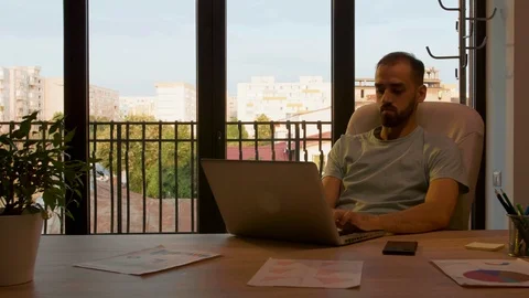 Silhouette of manager working in an office with big windows lit by warm sunset Stock Footage 114313952