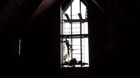 Silhouette of men working on scaffolding in front of large church window Stock Footage 33064043