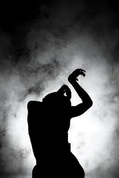Silhouette modern ballet dancer posing on dark background with smoke Stock Photos