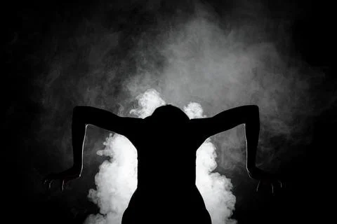 Silhouette modern ballet dancer posing on dark background with smoke Stock Photos