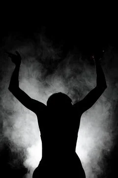 Silhouette modern ballet dancer posing on dark background with smoke Stock Photos