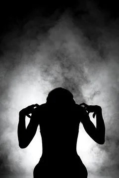 Silhouette modern ballet dancer posing on dark background with smoke Stock Photos
