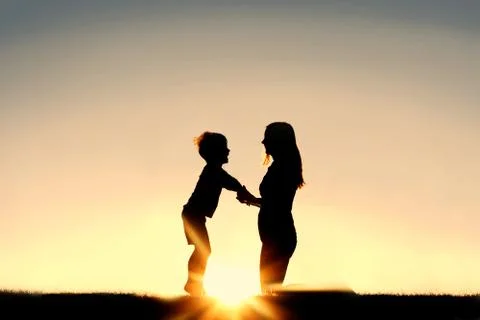 Silhouette of Mother and Young Child Holding Hands at Sunset Stock Photos