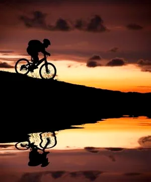 Silhouette of mountain biker with reflection and sunset Stock Photos
