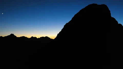 Silhouette of mountain ranges with crescent moon visible Stock Footage