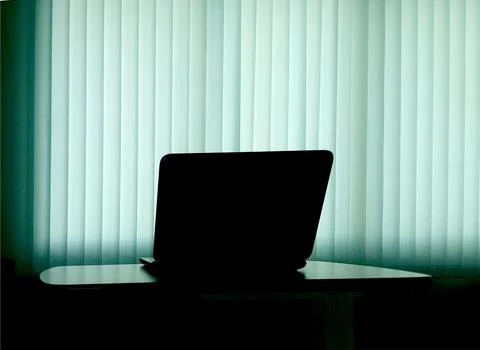 Silhouette notebook on table with blind light curtain Stock Photos