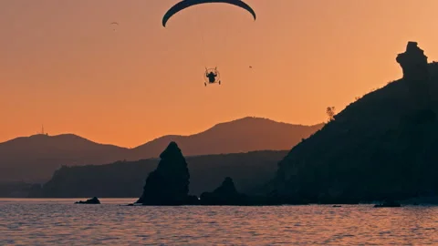 Silhouette of paramotor passing by during sunset at the beach Stock Footage 248489521