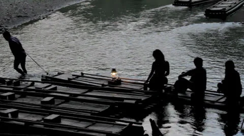 Silhouette people sitting on bamboo river raft being pulled Stock Footage 24273151