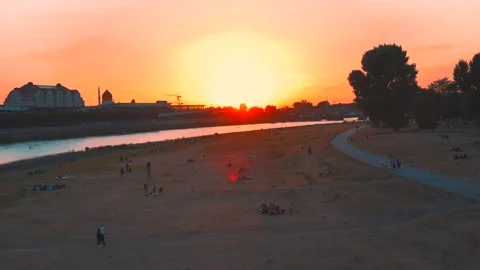 Silhouette of people sitting in the park by the river at sunset Stock Footage 203961553