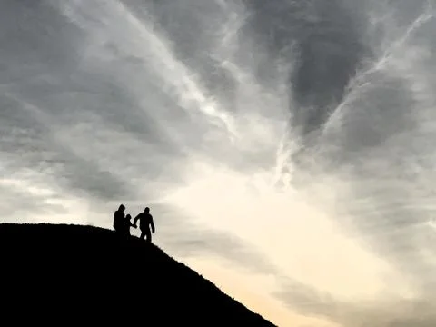 Silhouette of people on the top of the mountain. The family comes down the mo Stock Photos