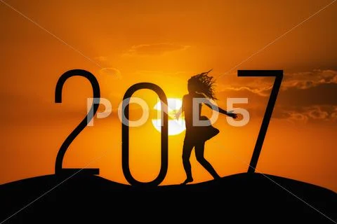 Silhouette person jumping over 2017 on the hill at sunset Stock Photos