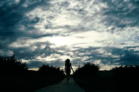 Silhouette of Person Walking Under Dramatic Sky Stock Photos