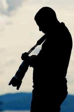 Silhouette of a photographer reviewing images on his camera right after sunset Stock Photos