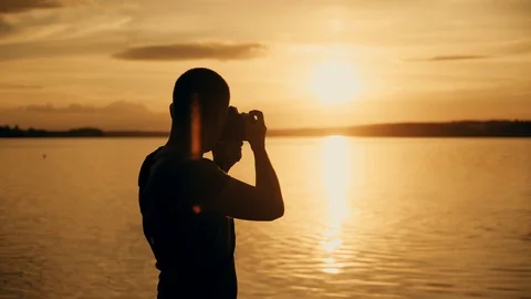 Silhouette of photographer taking photos in the river at sunset time. Stock Footage