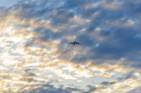 Silhouette of the plane in the clouds at sunset Stock Photos