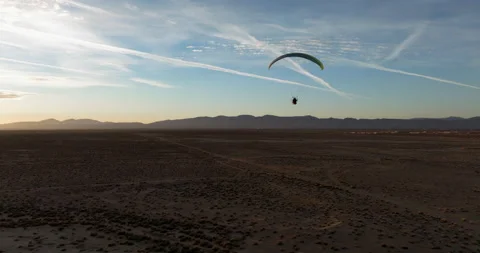Silhouette of a powered paraglider flying over the Mojave Desert at sunset Stock Footage 228664409