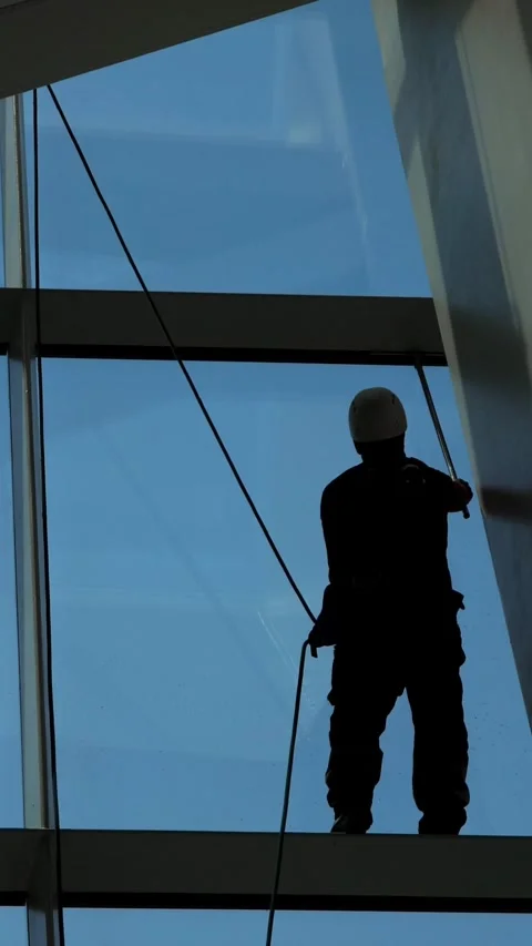 Silhouette of a professional window cleaner working on a skyscraper Video stock 341446323