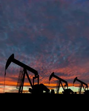 Silhouette of pumpjack against a dramatic sky Stock Photos