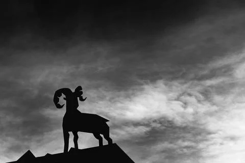 Silhouette of a ram on a rooftop against a dramatic sky at dusk Stock Photos