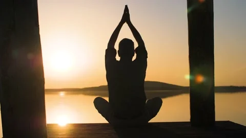 Silhouette of relaxed old man doing yoga in nature at a lake during sunset. Stock Footage 151394456