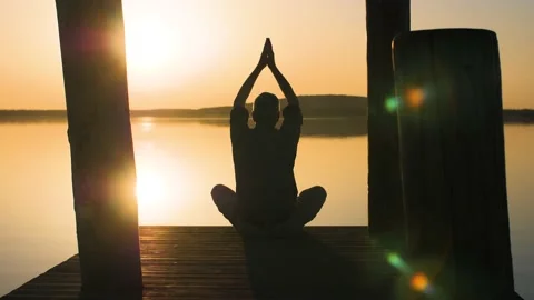Silhouette of relaxed old man doing yoga in nature at a lake during sunset. Stock Footage 151394664