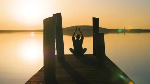 Silhouette of relaxed old man doing yoga in nature at a lake during sunset. Stock Footage 151421559