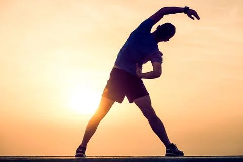 Silhouette of runner doing stretching at sunset Stock Photos