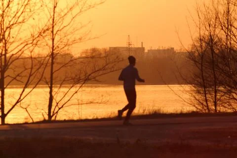 Silhouette of a runner during sunset. Stock Photos