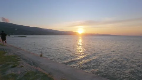 Silhouette of Runner by the lakeside at Sunset. Slow motion Stock Footage 303763378
