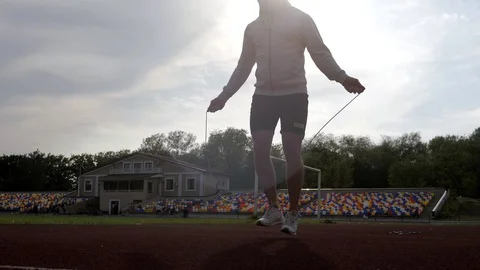 Silhouette of a runner warming up jumping with a jumping rope in the park in sun Stock-Footage 130138579