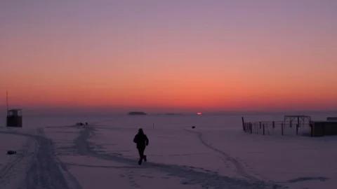 Silhouette of a running man at sunset time. Frozen river bank. Cold winter Stock Footage 72728419