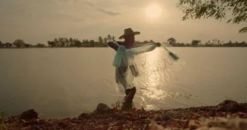 Silhouette scene of a native Asian male farmer is catching fish Stock Footage