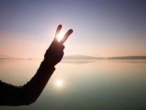 Silhouette of shape being made by hands with sunlight on beach. Stock Photos