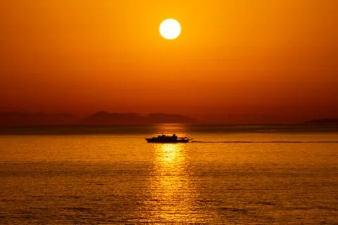 Silhouette of a ship passing in the reflection of the Sun in the Ionian Sea Stock Photos